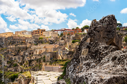 Blurred old town sunny summer cityscape behind ancient rock in Matera, Province of Matera, Basilicata Region, Italy