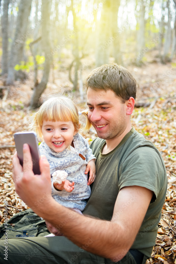 Dad and child make a video call online to family or friends and wave their hands at the camera.