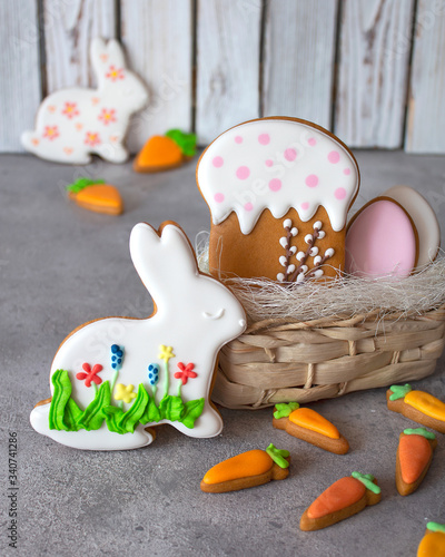 Easter gingerbread on a gray and wooden background with a wicker basket. Gingerbread in the form of a hare, carrot, egg and cake. Copy space. The concept of the Easter holiday and handmade. Vertical