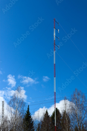 cellular antenna in the forest with bright blue sky on the background photo