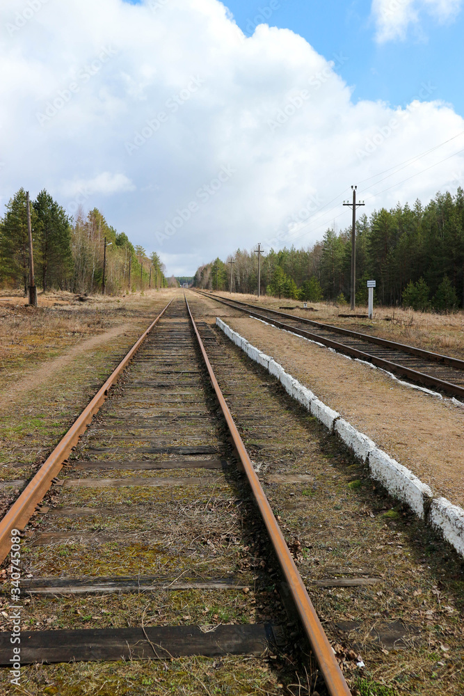 Spring view of old abandoned railway station and the rusty rails in the forest, Russia