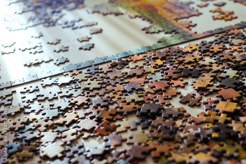 Scattered jigsaw puzzle pieces in natural colors. Lying on table. Concept of putting together disconnect elements.
