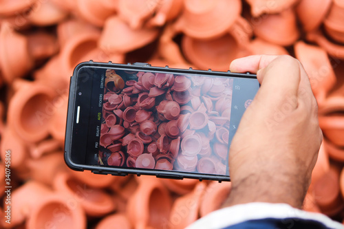 Photography Man taking photos of clay lamps (Diya) with his phone at a market in India for t