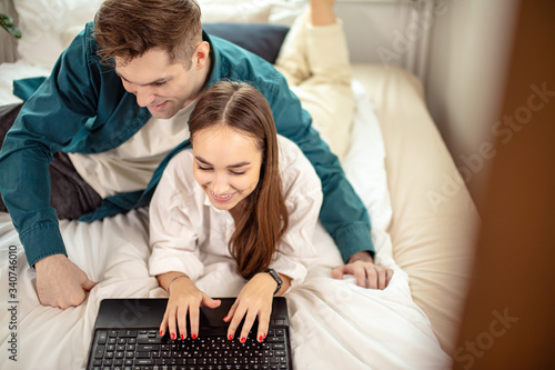 young caucasian married couple have free time at home together, have rest watching film on laptop. couple in casual domestic wear on bed. family, relationships, leisure time, rest, weekends concept