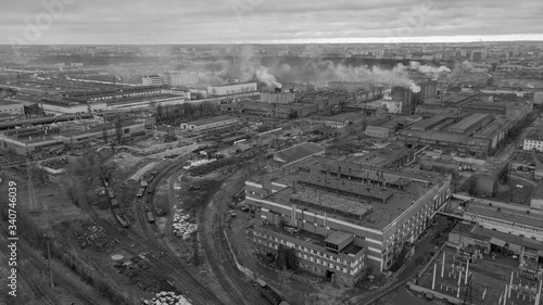 Aerial white and black photo of the workshops of the big factory with railway tracks on the dramatic sky background. Industrial and ecological concept.