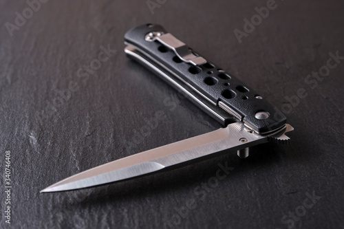 The folding knife is not fully decomposed against a dark background of stone.