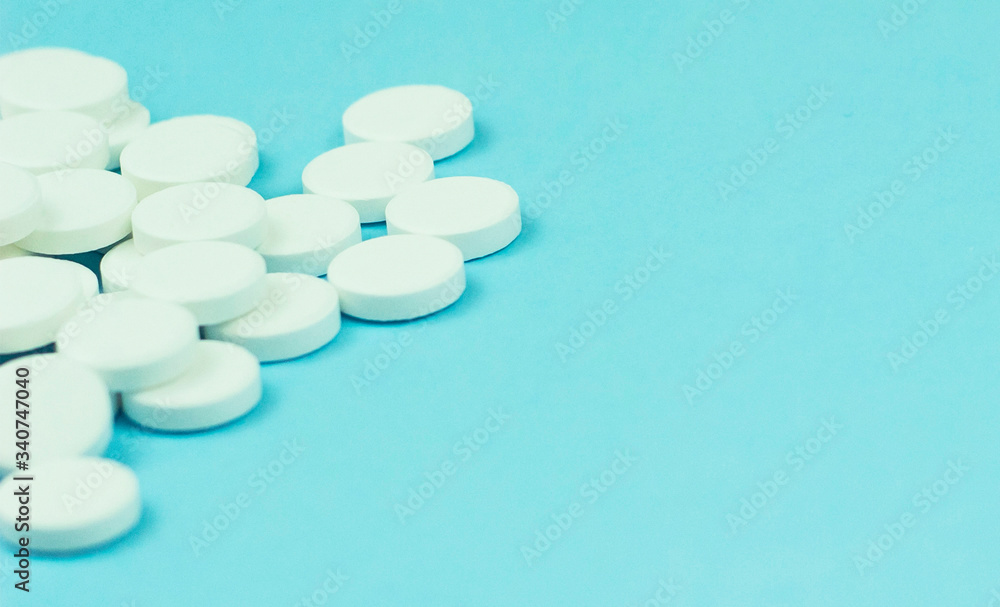 Close-up of many white pills on blue background