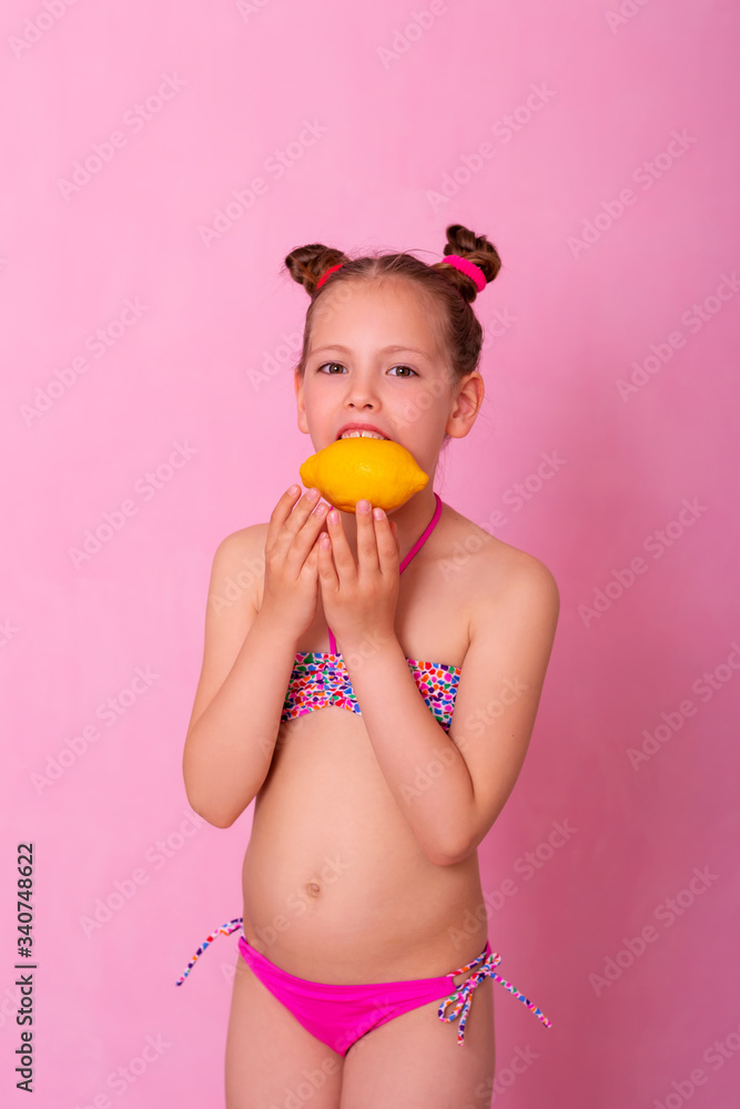 Young girl with lemon fruit. Little girl eating lemon isolated on pink background. Young girl with lemon fruit. Little girl eating lemon isolated on pink background.