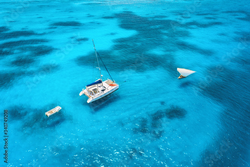 Aerial view of the yacht and sailboat in clear blue sea at sunset in summer. Top view of fishing boat, yachts, sandy beach, transparent water in Zanzibar. Travel. Tropical seascape. View from above © den-belitsky