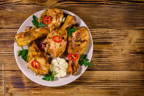 Baked chicken legs with parsley, garlic and sliced red hot pepper in a plate. Top view