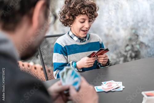 Father and son having fun playing card game sitting on the rooftop table in quarantine for the coronavirus lockdown. photo