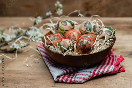 easter eggs in clay plate on a red checkered tablecloth on wooden background