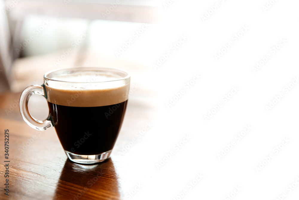 Glass Cup of coffee on a wooden table. Empty white background on the right.Office. Working remotely. Work from home. Cozy office at home. Glass Cup of coffee on a wooden table. Empty white background on the right.Office. Working remotely. Work from home. Cozy office at home.