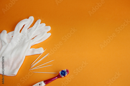white protective gloves toothpicks and a toothbrush on an orange background