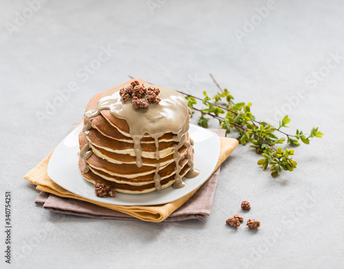 Pancake with nut paste and granola on a plate on a light background