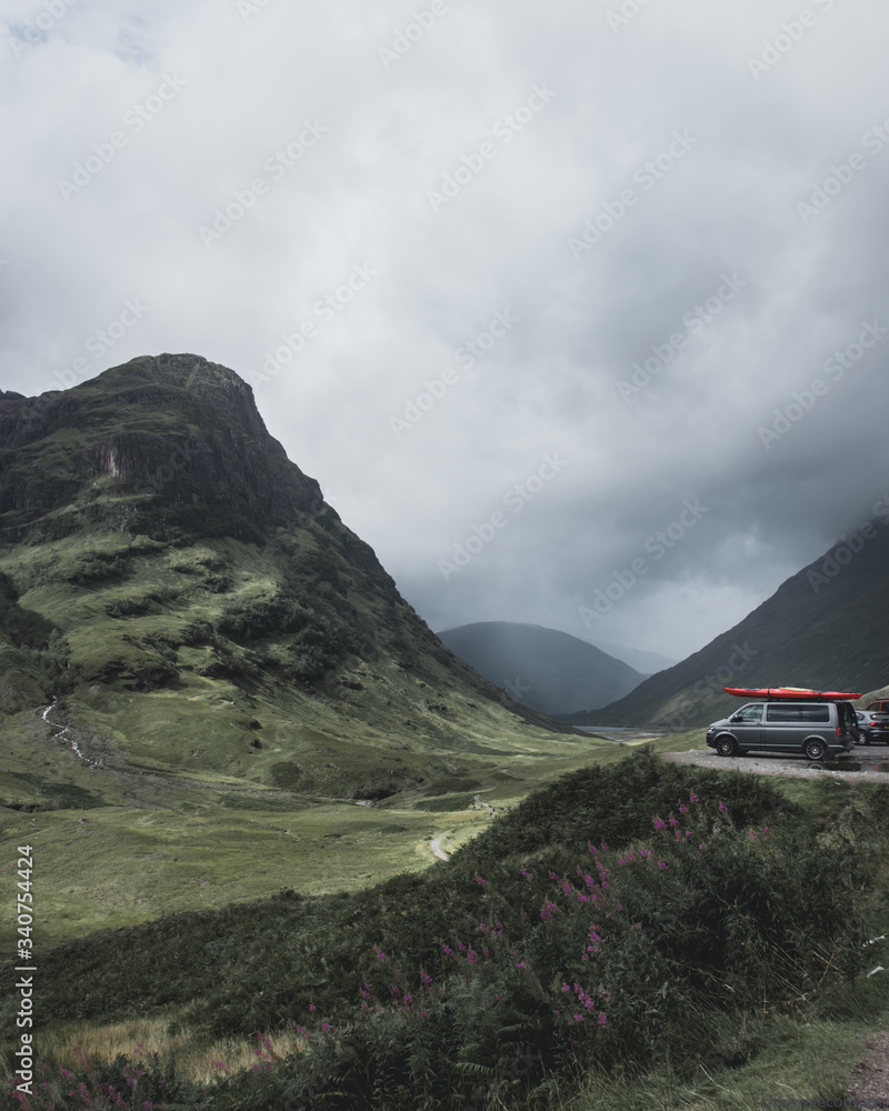 Camper-van parked with stunning views of a valley with green mountains