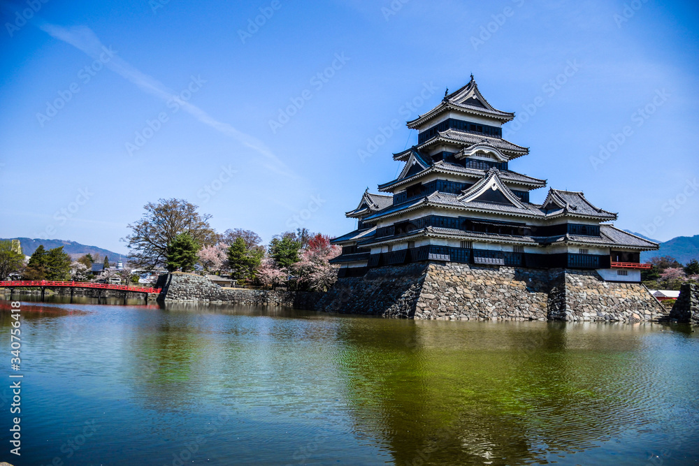 Fototapeta premium Iconic traditional japanese castle in the middle of turquoise lake in Matsumoto, Japan
