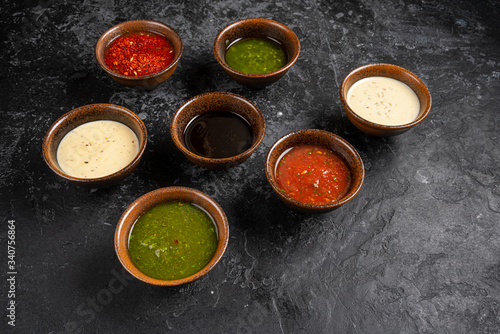 Set of different sauces with names on wooden background.