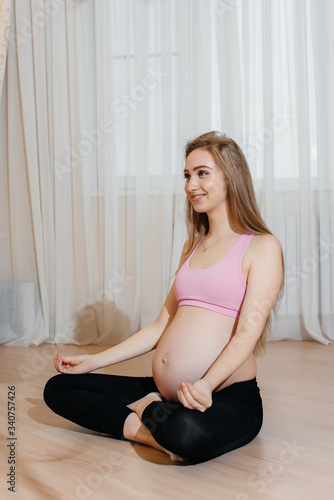 A pregnant girl does yoga at home. Health