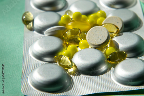 Spreading tablet of various shapes and colors, transparent yellow, large white. A bunch of pills. Unopened pharmacy blister with medicines. Vitamins, ascorbic acid, fish oil, omega 3. fight the virus