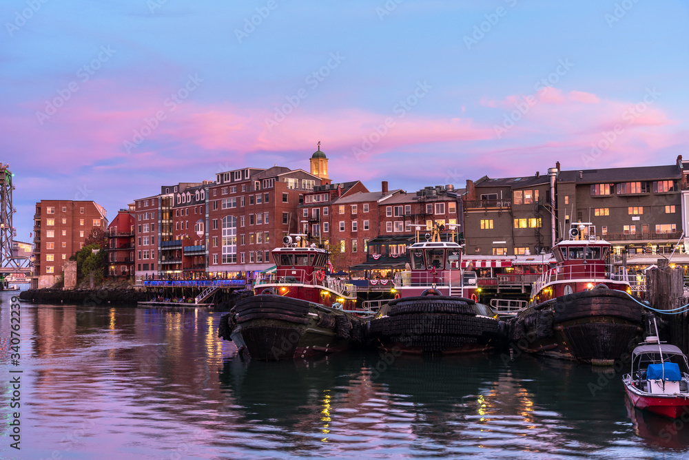 Portsmouth waterfront and skyline at twilight. Three tugboats are visible in foreground. New Hapshire, USA.
