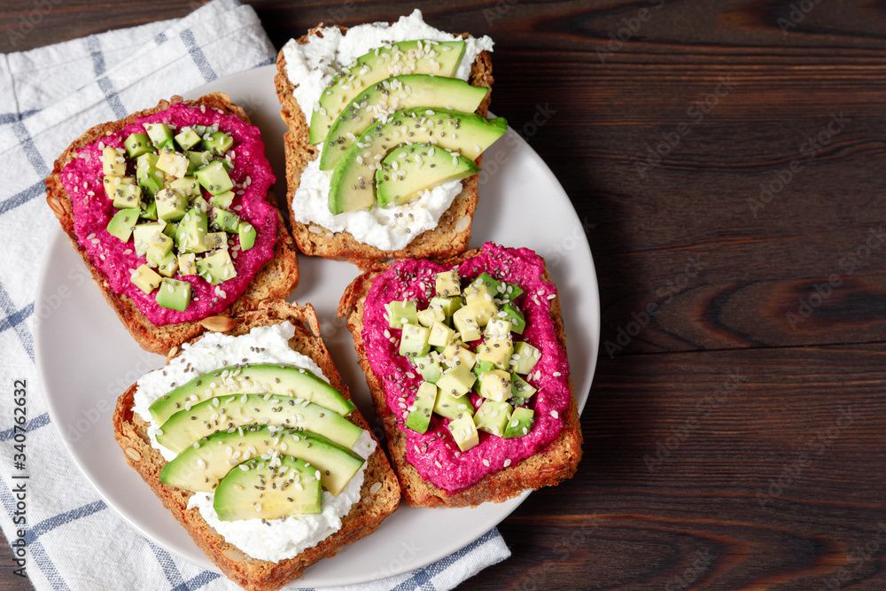 Variation of healthy sandwiches with avocado beetroot cream cheese and whole wheat rye bread on a plate. Delicious snacks and toast. Food composition, tasty italian meal. Close up, top view Variation of healthy sandwiches with avocado beetroot cream cheese and whole wheat rye bread on a plate. Delicious snacks and toast. Food composition, tasty italian meal. Close up, top view