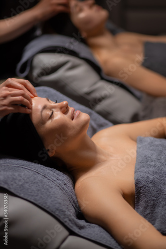 young and beautiful woman lie on massage desk, relax and enjoy, get healthy treatment of skin, in luxury wellness center