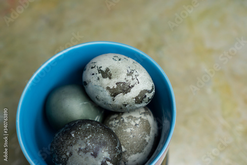 Blue pastel plate bowl with marble coloured Easter eggs table top view close-up on abstract background