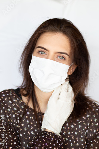 portrait of beautiful young woman wearing cotton white mask and medical/surgical gloves on white background. 