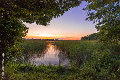 Fototapeta Naklejka Na Ścianę i Meble -  Beautiful and romantic sunset over an old bridge located on a lake in Mazury, also called as the region of lakes of Poland.