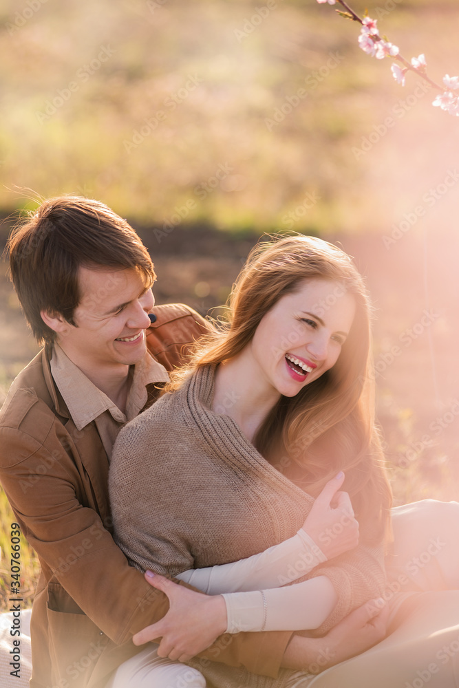 Romantic date of two beautiful lovers. A date near the blooming gardens. A young couple kisses on the street. Romantic date of two beautiful lovers. A date near the blooming gardens. A young couple kisses on the street.