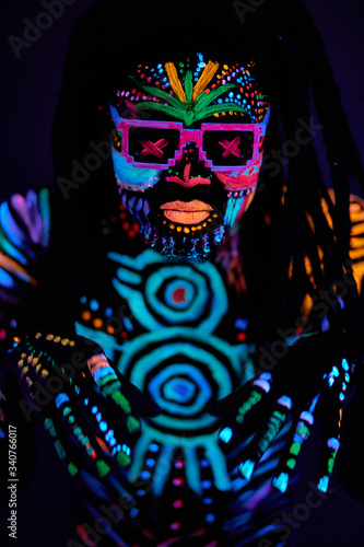bright UV body art, fluorescent paint, young african dancer man in sunglasses, dark isolated studio background
