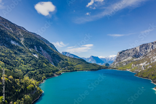 The Improbable aerial landscape of village Molveno, Italy, azure water of lake, empty beach, snow covered mountains Dolomites on background, roof top of chalet, sunny weather, a piers, coastline, © Vladimir Drozdin