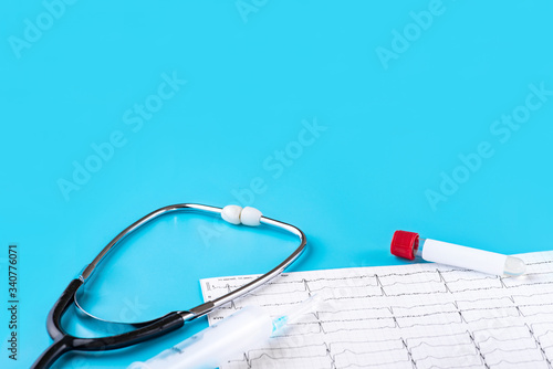 Stethoscope, syringe, cardiogram, and blood test tube for coronavirus on a blue background. The concept covid-19 or 2019-nCov.