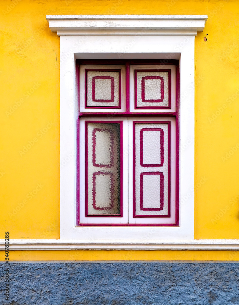 Half closed window in a yellow wall, detail of a classic villa design.