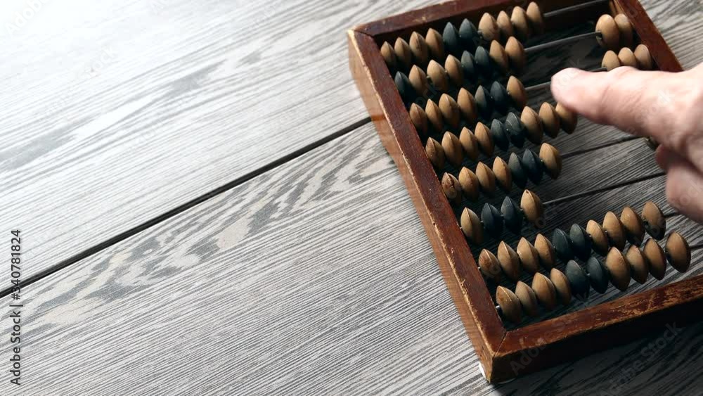A Elderly Man Moves Wooden Knuckles On A Outdated Vintage Wooden Abacus On A Gray Desk Panning Slider Shot, Close-up. Natural Daylight.. A Elderly Man Moves Wooden Knuckles On A Outdated Vintage Wooden Abacus On A Gray Desk Panning Slider Shot, Close-up. Natural Daylight..