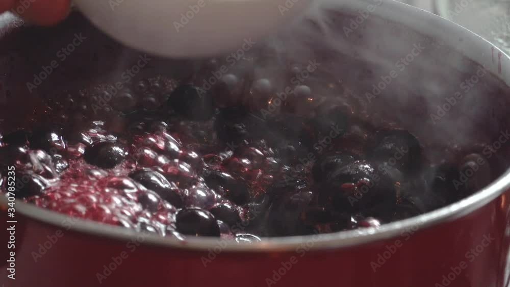 Cooking delicious red fruit jam, mixing and kneading. Close up