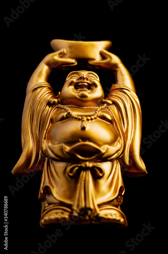 A low angle view of a small replica statue of The Buddha with a black background. Selective Focus on the face.
