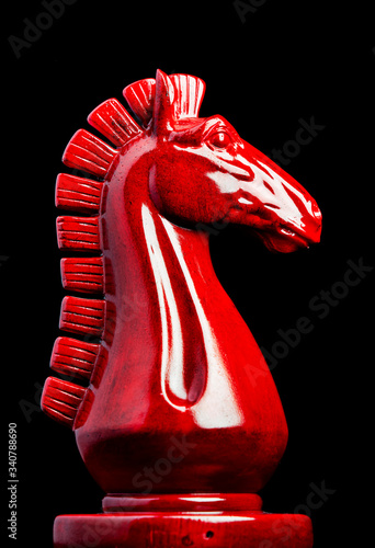 Wooden chess knight in red with black background