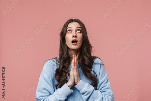 Image of astonished woman looking upward and holding palms together