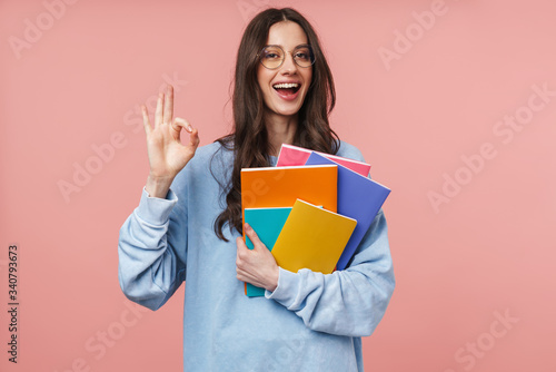 Image of attractive young student girl smiling and holding exercise books