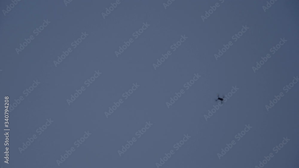 A slow motion of a drone rotating in air and then flying away from the frame. The sky is blue with no clouds on it. A slow motion of a drone rotating in air and then flying away from the frame. The sky is blue with no clouds on it.