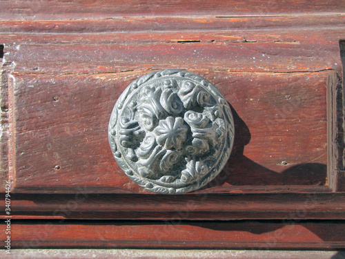 Old hardware on old natural wood door. Natural textured background and historical iron object illuminated by sunlight.