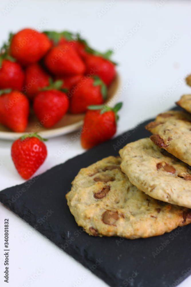 cookie with chocolate on plate and strawberry on light background. cookie with chocolate on plate and strawberry on light background.