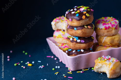Sprinkled mini donuts stacked with a dark background