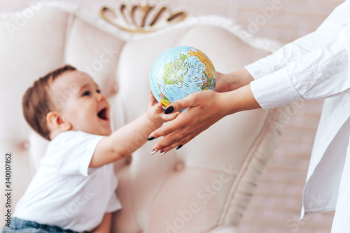Little boy with a globe, a child learns the world through a globe at home with parents studying at home while isolated