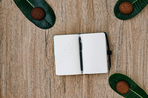 flat lay, Notepad with white paper, unfolded, lies on a wooden background, a pen on the back of a notebook. chocolate cookies for breakfast