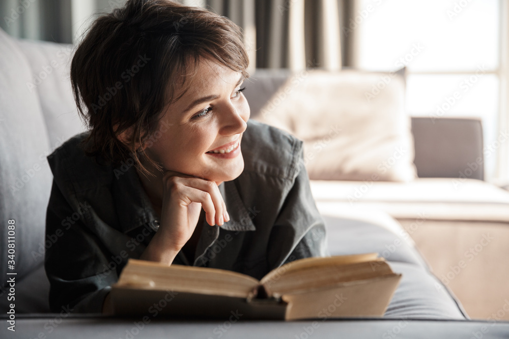 Image of caucasian cute pleased woman reading book and smiling Image of caucasian cute pleased woman reading book and smiling