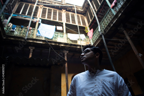 An young Indian Bengali detective with traditional wear looking upward inside an old vintage house in the morning. Indian lifestyle.