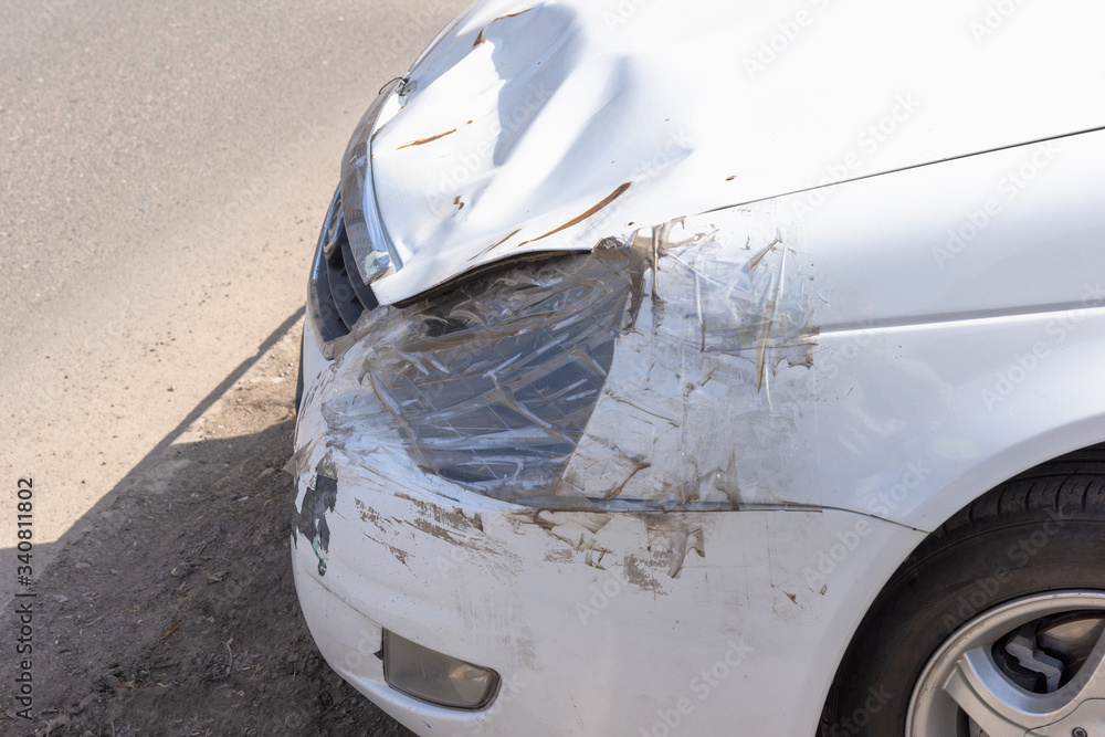 White car accident vehicle destroyed. Headlight sealed with tape and a plastic bag